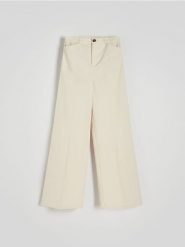 Szerokie spodnie z bawełny - złamana biel. Spodnie materiałowe damskie Reserved, bez wzorów, z bawełny. W wyprzedaży za 55.99 zł.