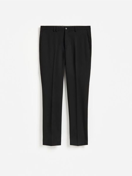 Garniturowe spodnie slim fit - czarny. Czarne spodnie wizytowe męskie Reserved, z tkaniny. Za 169.99 zł.