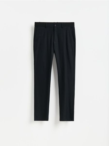 Gładkie spodnie chino slim - czarny. Czarne spodnie materiałowe męskie Reserved, bez wzorów, z bawełny. Za 159.99 zł.