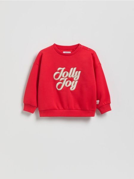 Bluza ze świątecznym napisem - czerwony. Czerwone bluzy i bluzki niemowlęce Reserved, bez wzorów, z bawełny, bez ramiączek, bez kaptura. Za 55.99 zł.