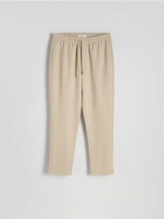 Spodnie regular fit - złamana biel. Spodnie materiałowe męskie Reserved, bez wzorów, z dzianiny. W wyprzedaży za 89.99 zł.