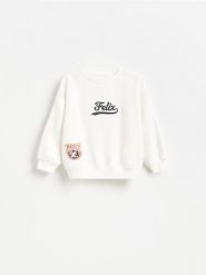 Bluza Felix the Cat - złamana biel. Bluzy i bluzki niemowlęce Reserved, bez wzorów, z bawełny, bez ramiączek, bez kaptura. Za 49.99 zł.