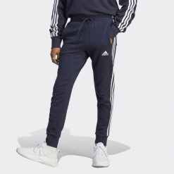 Spodnie dresowe męskie adidas Essentials French Terry Tapered Cuff 3-Stripes. Białe spodnie dresowe męskie Adidas, bez wzorów, z dresówki. Za 182.00 zł.