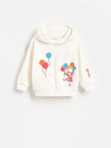 Bluza z aplikacją Basia - złamana biel. Bluzy i bluzki niemowlęce Reserved, z aplikacjami, z bawełny, bez ramiączek, bez kaptura. Za 59.99 zł.