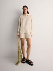 Szorty z lnem - kremowy. Białe szorty damskie Reserved, bez wzorów, z tkaniny. W wyprzedaży za 49.99 zł.