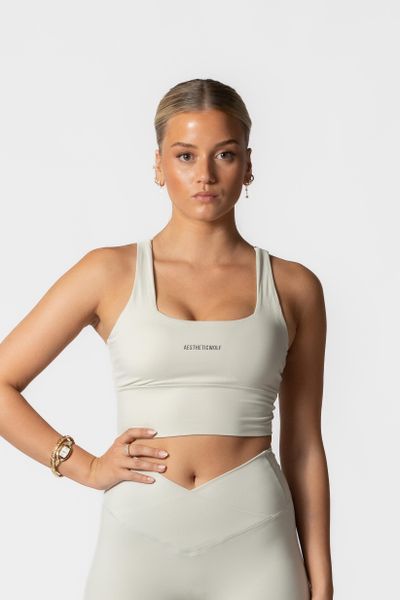 Damski stanik sportowy z krzyżowanymi plecami – kremowy. Białe biustonosze sportowe damskie AESTHETIC WOLF, bez wzorów, z dzianiny. Za 109.99 zł.