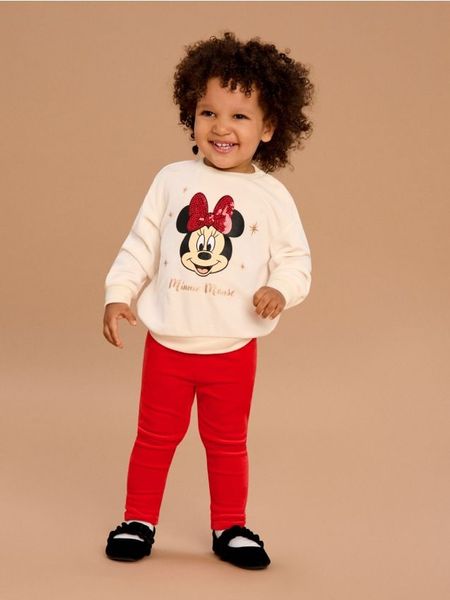 Komplet: bluza i spodnie Minnie Mouse - kremowy. Białe bluzy i bluzki niemowlęce Sinsay, bez wzorów, bez ramiączek, bez kaptura. W wyprzedaży za 19.99 zł.