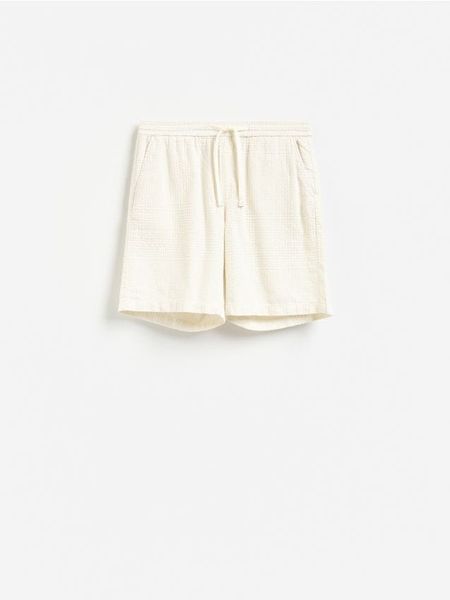 Bawełniane szorty jogger - złamana biel. Szorty męskie Reserved, z bawełny, bez kołnierzyka. Za 129.99 zł.