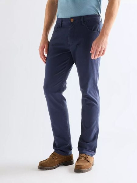 MĘSKIE SPODNIE WRANGLER GREENSBORO NAVY 112378468. Niebieskie spodnie materiałowe męskie Wrangler, bez wzorów, z materiału. Za 219.99 zł.