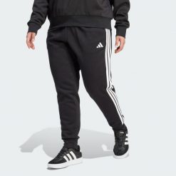 Spodnie Essentials 3-Stripes Fleece Slim (Plus Size). Czarne spodnie dresowe damskie Adidas, plus size, bez wzorów, z polaru. Za 219.00 zł.
