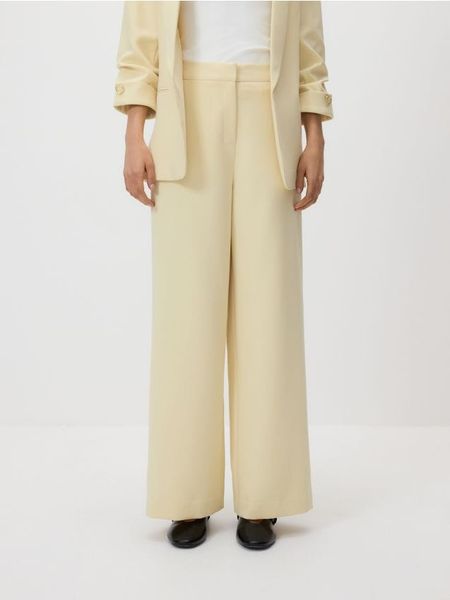 Spodnie z szerokimi nogawkami - jasnożółty. Żółte spodnie materiałowe damskie Reserved, bez wzorów, z tkaniny. Za 119.99 zł.