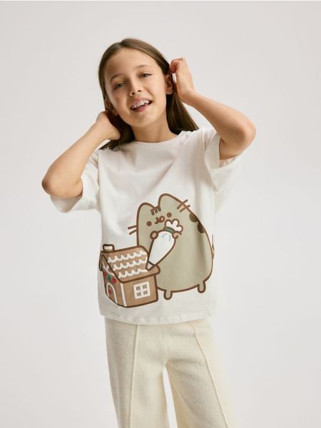 T-shirt ze świątecznym nadrukiem Pusheen - złamana biel. Koszulki dziewczęce Reserved, bez wzorów, z bawełny, bez ramiączek. W wyprzedaży za 19.99 zł.