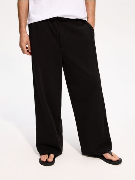 Spodnie loose fit - czarny. Czarne spodnie materiałowe męskie Reserved, bez wzorów, z bawełny. Za 129.99 zł.