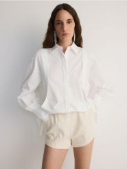 Szorty z bawełnianej tkaniny - złamana biel. Szorty damskie Reserved, bez wzorów, z bawełny. W wyprzedaży za 79.99 zł.