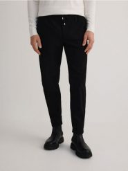 Spodnie carrot fit - czarny. Czarne spodnie materiałowe męskie Reserved, bez wzorów, z bawełny. W wyprzedaży za 89.99 zł.