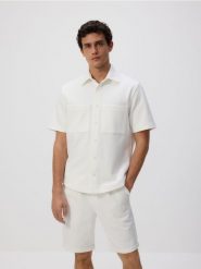 Szorty regular fit - złamana biel. Szorty męskie Reserved, z bawełny, bez kołnierzyka. Za 99.99 zł.