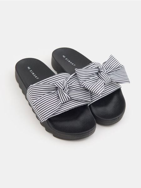 Klapki w paski z kokardą - czarny. Czarne klapki damskie Sinsay, bez wzorów, bez obcasa. Za 39.99 zł.