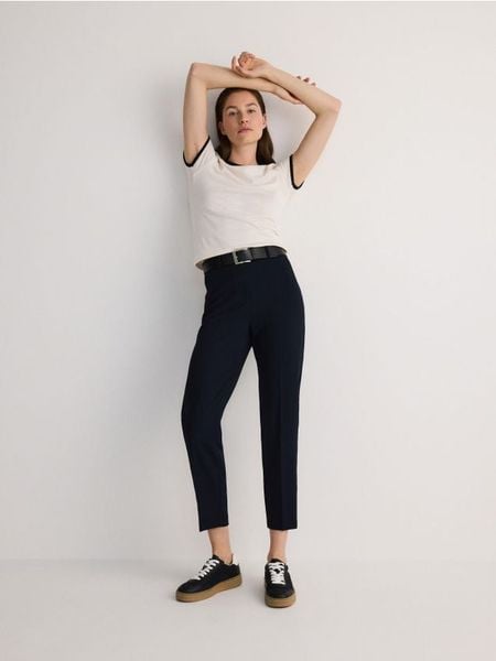 Spodnie z paskiem - granatowy. Niebieskie spodnie materiałowe damskie Reserved, bez wzorów, z tkaniny. W wyprzedaży za 79.99 zł.