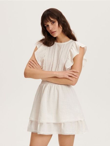 Bawełniana sukienka mini - złamana biel. Sukienki damskie Reserved, l, bez wzorów, z bawełny, bez kołnierzyka, bez ramiączek, mini. W wyprzedaży za 49.99 zł.