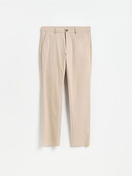 Gładkie spodnie chino slim - beżowy. Brązowe spodnie materiałowe męskie Reserved, bez wzorów, z bawełny. Za 159.99 zł.