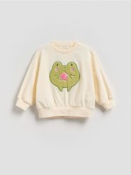 Bawełniana bluza z aplikacją - kremowy. Białe bluzy i bluzki niemowlęce Reserved, z aplikacjami, z bawełny, bez ramiączek, bez kaptura. Za 55.99 zł.