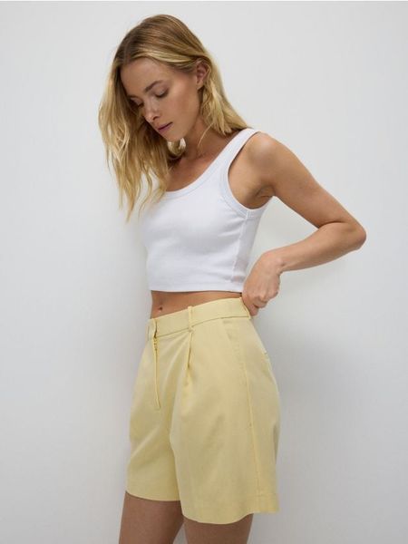 Szorty z kantem - jasnożółty. Żółte szorty damskie Reserved, bez wzorów, z tkaniny. W wyprzedaży za 59.99 zł.
