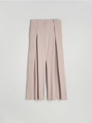 Luźne spodnie z zakładkami - brązowy. Brązowe spodnie materiałowe damskie Reserved, bez wzorów, z tkaniny. W wyprzedaży za 99.99 zł.