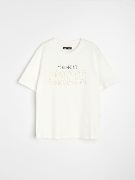 Bawełniana koszulka z perłową aplikacją - kremowy. Białe t-shirty damskie Sinsay, l, z aplikacjami, z bawełny, bez kołnierzyka. Za 29.99 zł.