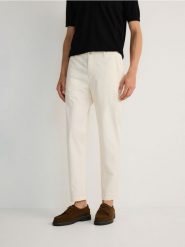 Bawełniane spodnie chino slim - złamana biel. Spodnie materiałowe męskie Reserved, bez wzorów, z bawełny. W wyprzedaży za 119.99 zł.