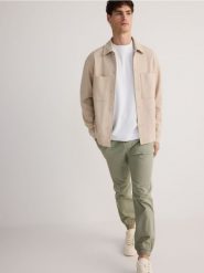 Spodnie jogger slim - oliwkowy. Zielone spodnie materiałowe męskie Reserved, bez wzorów, z bawełny. W wyprzedaży za 99.99 zł.