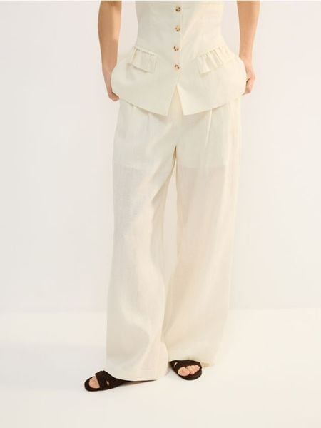 Lniane spodnie - złamana biel. Spodnie materiałowe damskie Reserved, bez wzorów, z tkaniny. Za 239.99 zł.