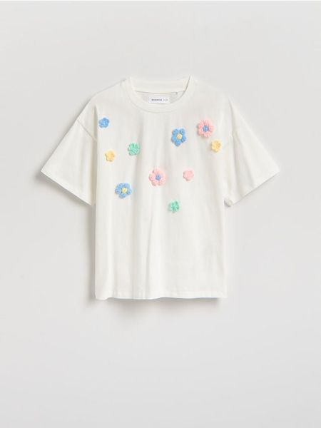 Bawełniany t-shirt z aplikacją 3d - złamana biel. Koszulki dziewczęce Reserved, z aplikacjami, z bawełny, bez ramiączek. Za 45.99 zł.