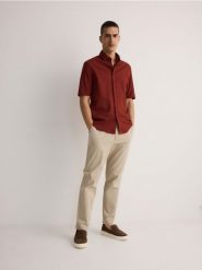 Spodnie chino slim - beżowy. Brązowe spodnie materiałowe męskie Reserved, bez wzorów, z lyocellu. W wyprzedaży za 79.99 zł.